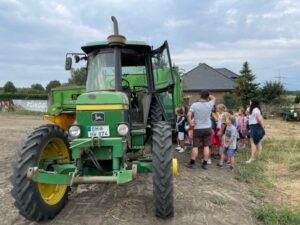 Schulklasse beim Bauernhofbesuch an einem Traktor